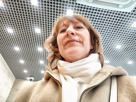 Middle-Aged Woman Captures Selfie While Shopping Indoors. Smiling adult shopper takes self-portrait during an indoor shopping trip