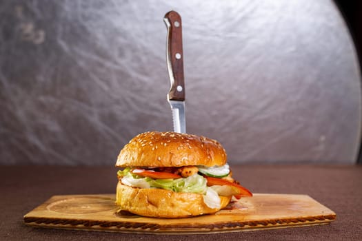 knife stuck in a juicy burger with meatballs.