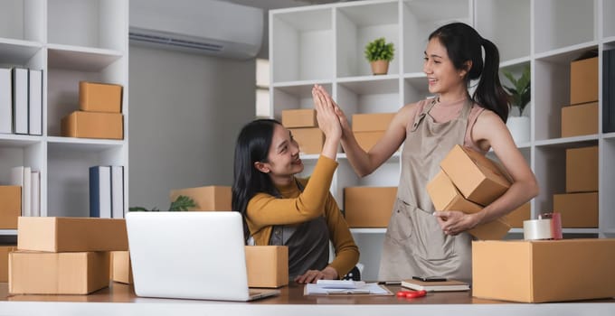 Asian businesswomen giving high-five in office. Concept of teamwork and business celebration.