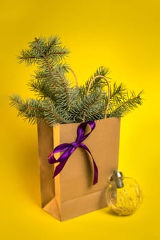 Christmas gift packaging with spruce branches on a yellow background.