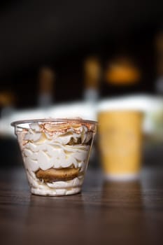 dessert in a plastic cup against the background of coffee in a cafe.