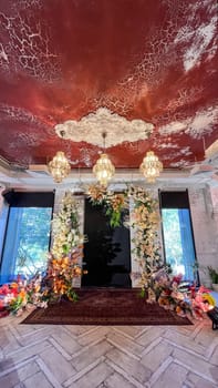 A beautiful wedding venue with a floral arch, chandeliers and a red carpet. Perfect for a romantic wedding ceremony or reception.