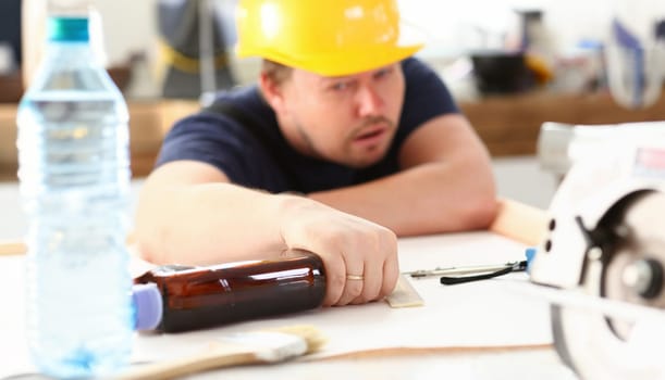 Arm of drunken worker in yellow helmet hold liquor bottle portrait. Manual job workplace DIY inspiration fix shop hard hat industrial education profession career