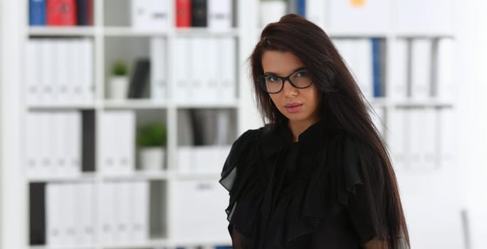 Beautiful smiling brunette woman in office posing arms crossed on chest wearing stylish glasses portrait. White collar worker at workspace officer highly pay smart serious job offer headhunter hr
