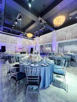 A large, elegant wedding reception hall with round tables, crystal chandeliers, and a balcony overlooking the dance floor.