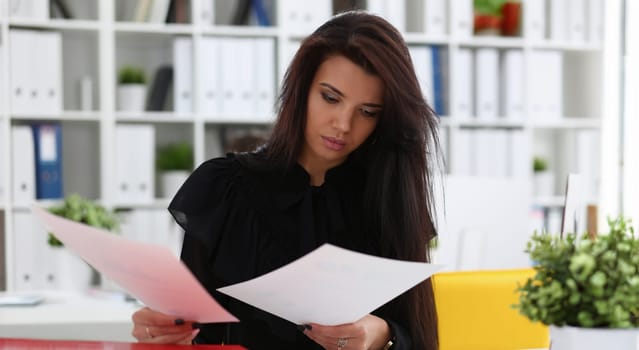 Beautiful smiling brunette woman sit at table hold in arm papers portrait colleagues in background. White collar worker at workspace officer highly pay smart serious headhunter offer