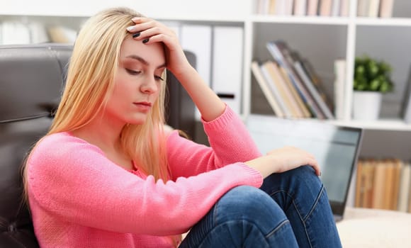 Unhappy lonely depressed woman at home, she is sitting on the couch, depression concept