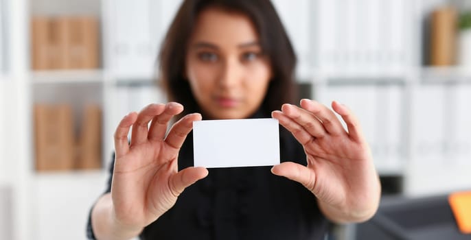 portrait of young beautiful brunette chinese businesswoman work in office show cutaway business card