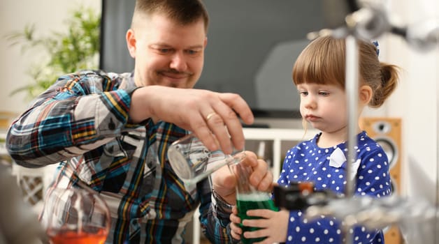 Man and little girl play with colourful liquids portrait. Young team clean research equipment colour reagent food additions flavor activity flavour concept