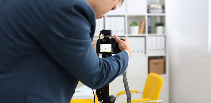 Male arms in suit mount camcorder to tripod making promo videoblog or photo session in office closeup. Vlogger adjust set up and check image quality to show job offer promotion selfie information