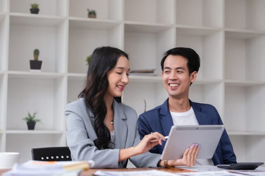 A young businessman and a female Asian accountant are discussing financial accounting and business planning together in the office..