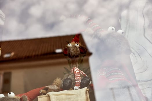 Whimsical New Year's Mouse in Cap and Scarf Stands Behind Store Display. Capture the charm of the holiday season with this delightful image featuring a toy mouse or rat wearing a comical New Year's cap and scarf, playfully standing behind a shop window display. The festive scene adds a touch of whimsy to your creative projects, invoking the spirit of celebration and joy.