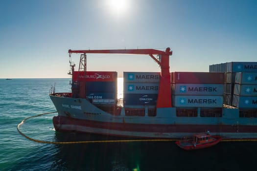 Aerial view of a RISE SHINE container cargo ship stands aground after a storm with floating boom around the ship to prevent the spread of petroleum. Container ship ran aground during the storm.