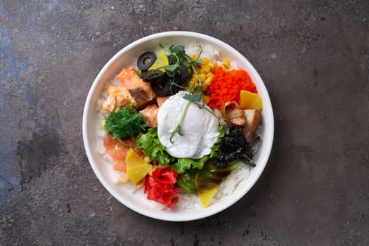 Fresh healthy food ingredients on white plate over dark background. Cucumber, carrot, shrimp, egg, cherry tomatoes, avocado, cabbage, rice.