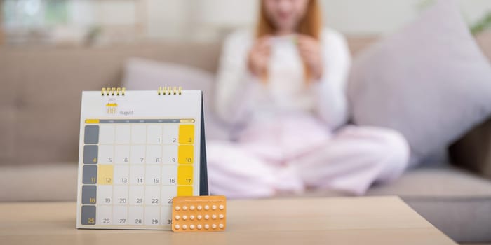 Birth control pills with calendar on table at home. Concept of contraception, family planning, and women's healthcare.