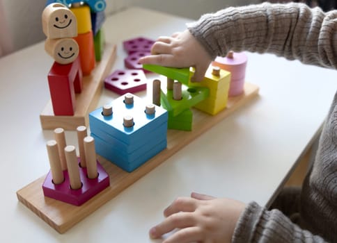 Child playing a fun-filled game of logic with colourful wooden blocks. Game of logic. Educational games for children and earlier development.