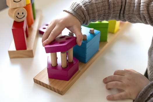 Child playing a fun-filled game of logic with colourful wooden blocks. Game of logic. Educational games for children and earlier development.