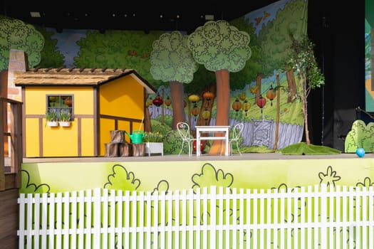 Easter decoration for children on stage with a yellow house and a large easter egg. Children's theater.