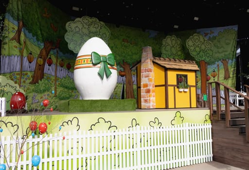Easter decoration for children on stage with a yellow house and a large easter egg. Children's theater.