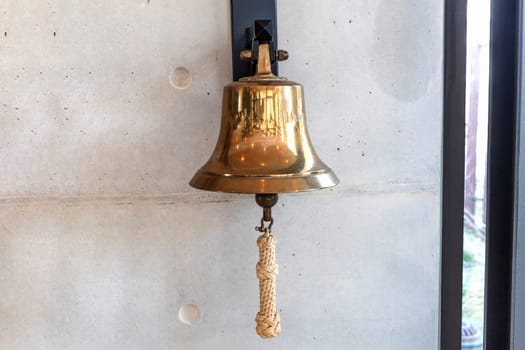 Brass bell on a gray wall indoors. High quality photo