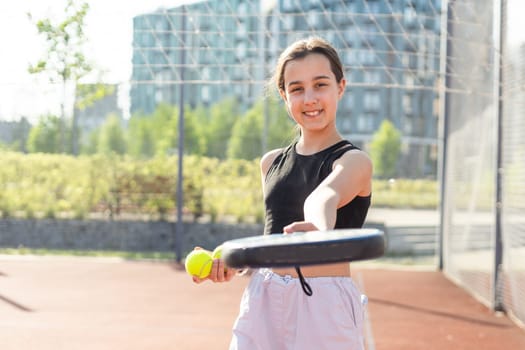 Padel tennis player with racket and ball in hands. Girl athlete with paddle racket on court outdoors. Sport concept. Download a high quality photo for the design of a sports app or web site. High quality photo