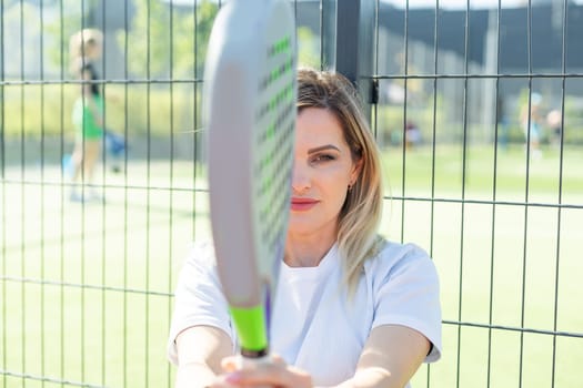 Happy female paddle tennis player during practice on outdoor court looking at camera. Copy space. High quality photo