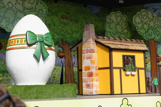 Easter decoration for children on stage with a yellow house and a large easter egg. Children's theater.