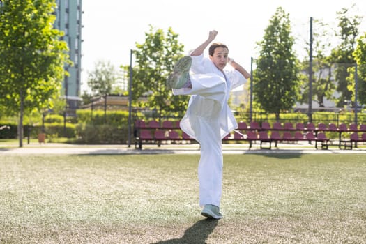 Young active girl wearing in white kimono with white belt performing martial arts kick skills. sporty karate woman improving fight technique on Chinese bridge. concept of sport. High quality photo