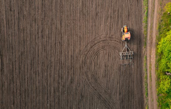 Tractor plows field in the spring. Aerial top view, Wheat seed planting company