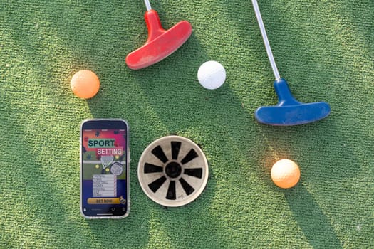 golf equipment on the green lawn. mini golf sports betting on a smartphone. High quality photo
