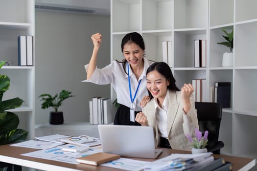 Happy businesswomen celebrating success in a modern office. Concept of teamwork, achievement, and corporate victory.