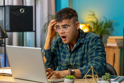 Frustrated Indian man having software problems with laptop angry guy nervous seeing error or mistake notification at computer screen mad employee experience virus attack or app malfunction. Lifestyle