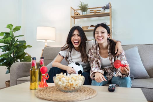 Gay lesbian woman couple, two friends enjoying watching football game, happy after the team they were cheering for wins at home. World Cup concept, couple lgbt concept.