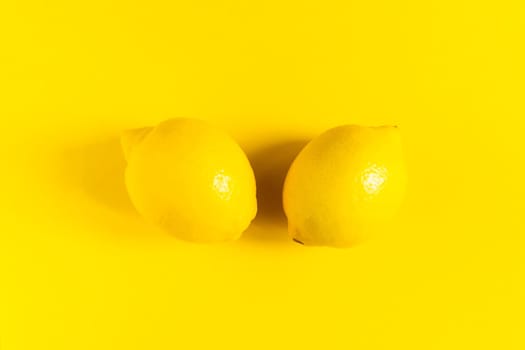 Juicy lemons on a bright yellow background, citrus minimal concept. Flat lay, top view, copy space.