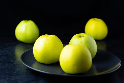 Fresh ripe green apples on a wooden table against dark background, space for text