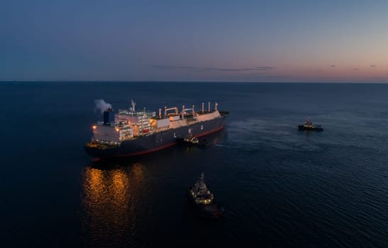 A large LNG tanker docks at an industrial port terminal for cargo operations at dusk