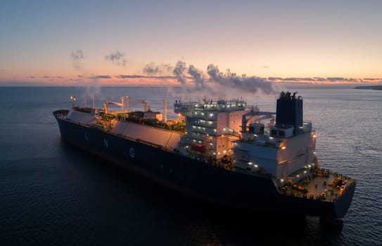 A large LNG tanker docks at an industrial port terminal for cargo operations at dusk