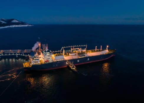 A large LNG tanker docks at an industrial port terminal for cargo operations at dusk