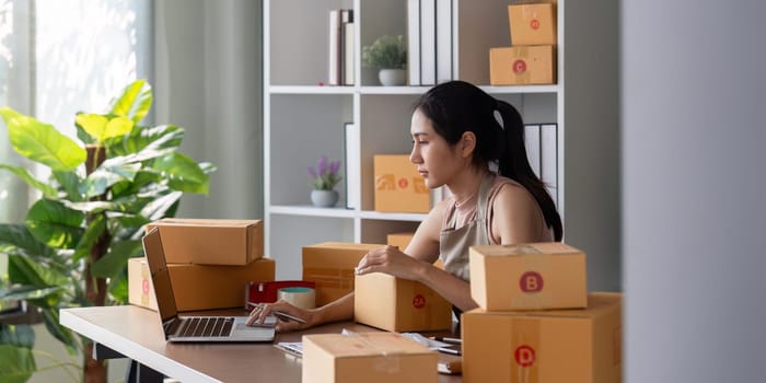 Small business owner preparing packages for shipment at home office. Concept of ecommerce, online sales, and entrepreneurship.