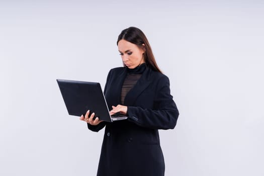 Attractive blond hair woman wearing business suit sitting in front of a computer with angry facial expression holding a hammer and wearing glasses