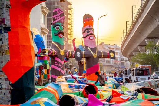 Jaipur, Rajasthan, India - 22nd oct 2023: poor indian laborer standing in front of huge colorful paper effigies of Ravan made on the hindu festival of Dussehra in India