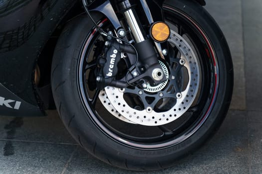 Wroclaw, Poland - August 4, 2023: A detailed view of the front wheel of a black Suzuki GSX motorcycle, showcasing the tire treads and brake system.
