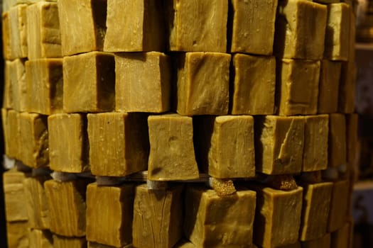 A close-up view of handmade laundry soap blocks, stacked neatly in a market stall, showcasing their rustic texture and natural appearance.