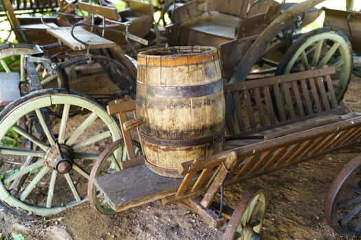 An old-fashioned wooden cart carrying a wooden barrel on top of it.