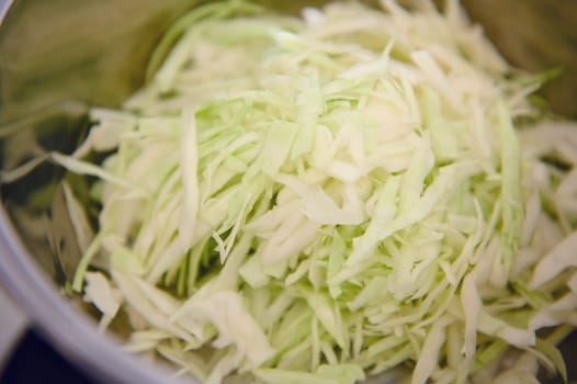 Close-up view. Chopped raw juicy cabbage in stainless steel saucepan. Directly above