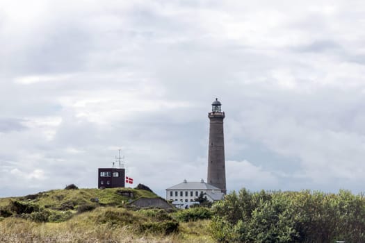 Natural landscape with lighthouse. Sand dunes covered with bushes and grass. Skagen, Denmark