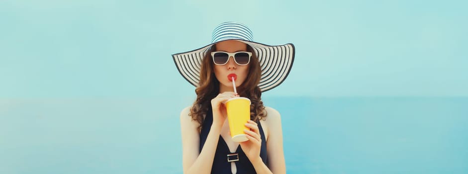 Summer portrait of beautiful young woman model drinking fresh juice wearing swimsuit, straw hat on the beach on sea background
