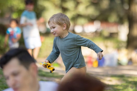 A young boy is running with a toy car in his hand. He is smiling and he is enjoying himself