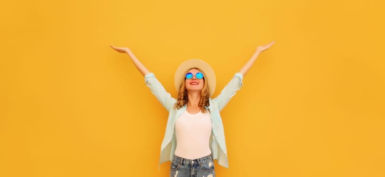 Summer holidays, inspired happy cheerful smiling young woman raising her hands up wearing denim clothing, straw hat on colorful yellow background