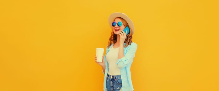 Happy cheerful smiling young woman calling on mobile phone with cup of coffee wearing summer straw hat on yellow background